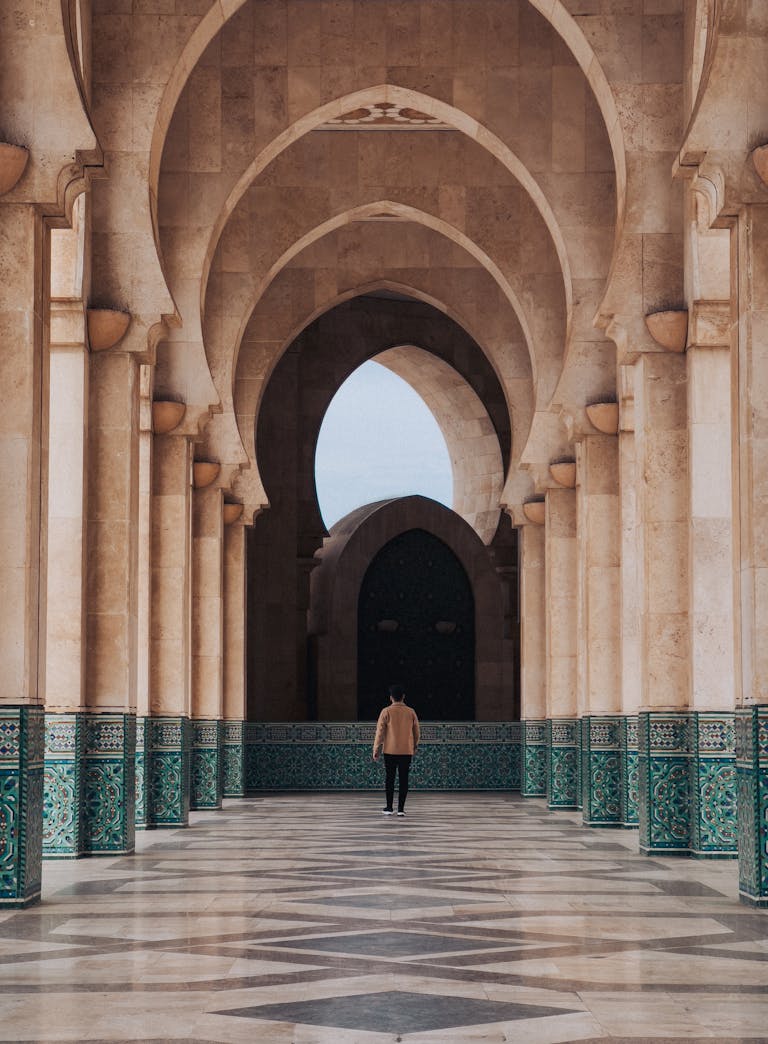 Man in a Brown Jacket Walking Through a Mosque